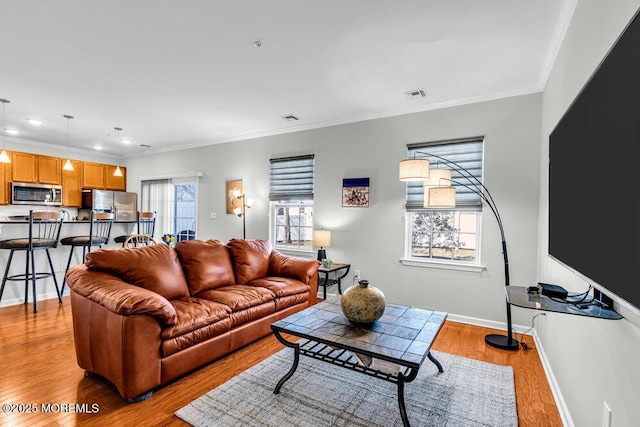 living area with baseboards, visible vents, recessed lighting, crown molding, and light wood-type flooring