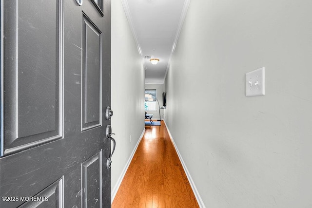 corridor featuring crown molding, baseboards, and wood finished floors