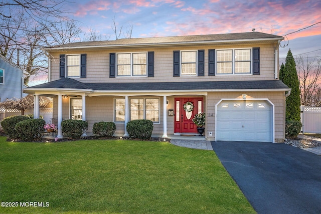 view of front of home with a front lawn, driveway, fence, roof with shingles, and a garage