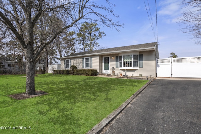 single story home featuring a front lawn, a gate, fence, and aphalt driveway