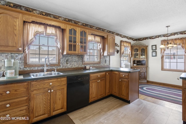 kitchen with a sink, brown cabinets, dark countertops, and dishwasher