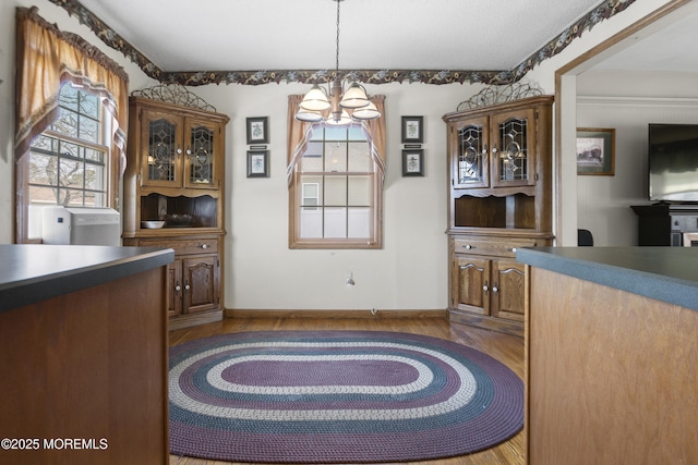 dining space with baseboards, an inviting chandelier, and wood finished floors