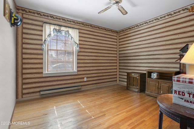 interior space with rustic walls, a ceiling fan, a baseboard heating unit, and light wood-style floors