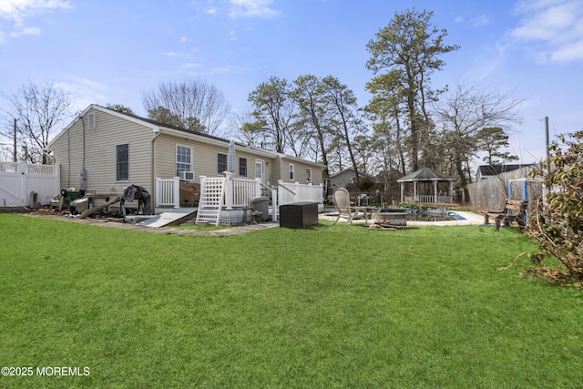 back of house with a fire pit, fence, a gazebo, a yard, and a deck