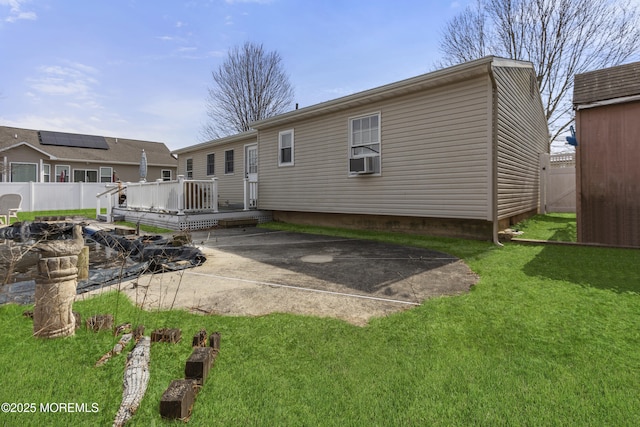 back of house featuring a patio area, a lawn, a wooden deck, and fence