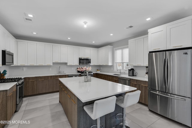 71 Broadway Ave, Lakewood, NJ 08701 - kitchen featuring a sink, stainless steel appliances, white cabinetry, light countertops, and a kitchen island