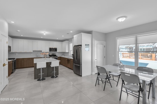 71 Broadway Ave, Lakewood, NJ 08701 - kitchen featuring a sink, stainless steel appliances, an island with sink, light countertops, and white cabinets