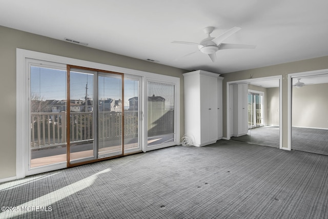 carpeted spare room featuring visible vents and ceiling fan