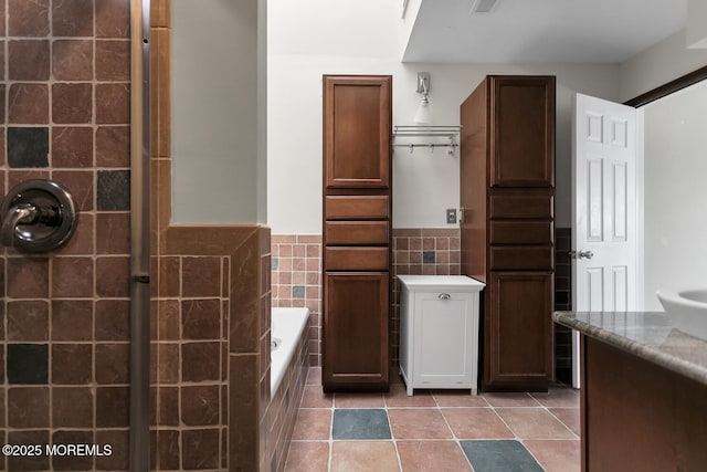 full bath featuring tile patterned flooring, visible vents, a garden tub, wainscoting, and tile walls