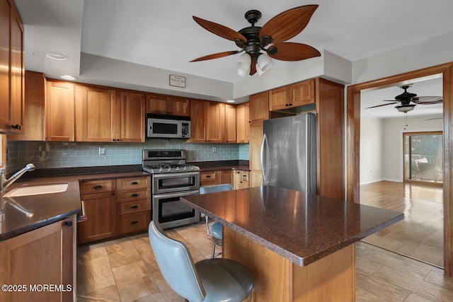 kitchen with tasteful backsplash, stainless steel appliances, a ceiling fan, and a sink