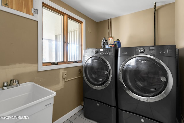 laundry area with light tile patterned floors, baseboards, laundry area, a sink, and washing machine and dryer