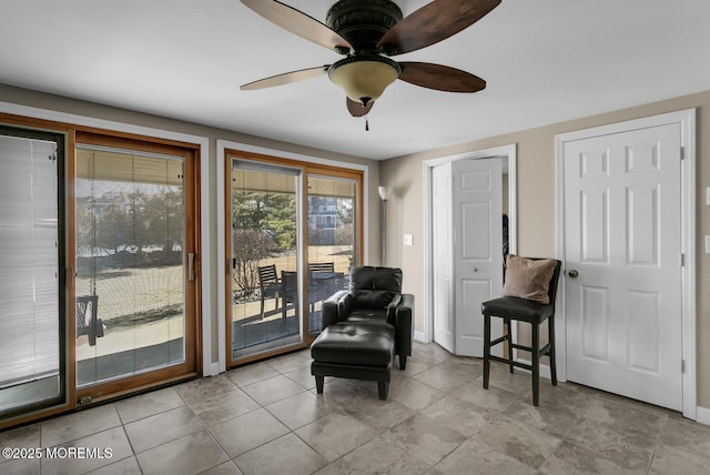 living area with a ceiling fan and baseboards