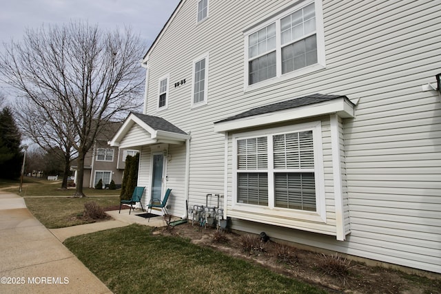 exterior space featuring a front yard and a shingled roof