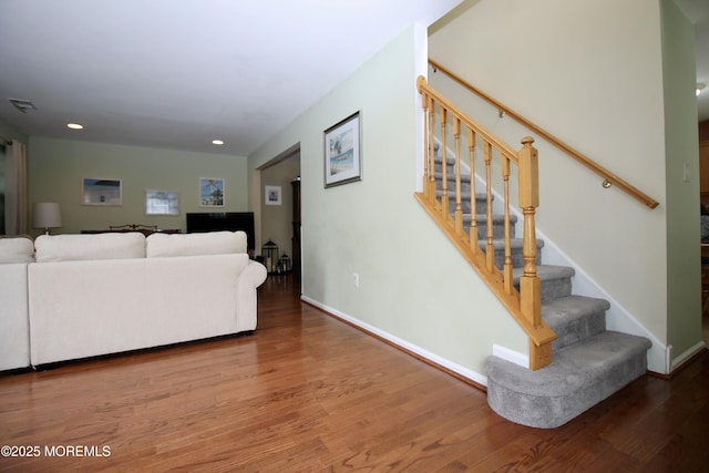 living room featuring visible vents, stairway, baseboards, and wood finished floors