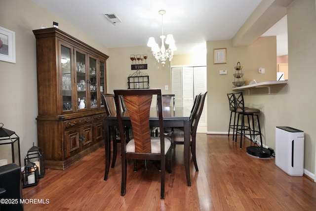 dining space featuring an inviting chandelier, wood finished floors, visible vents, and baseboards