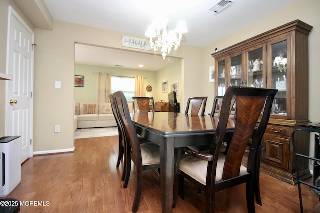 dining room featuring visible vents, baseboards, an inviting chandelier, and wood finished floors