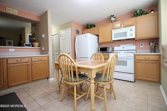 kitchen featuring light tile patterned flooring, white appliances, and light countertops