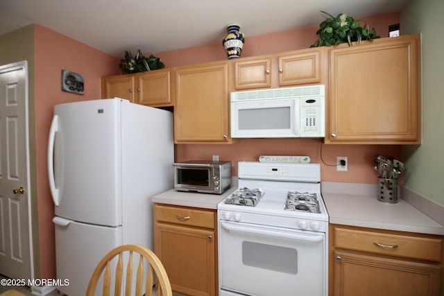 kitchen with light brown cabinets, a toaster, white appliances, and light countertops