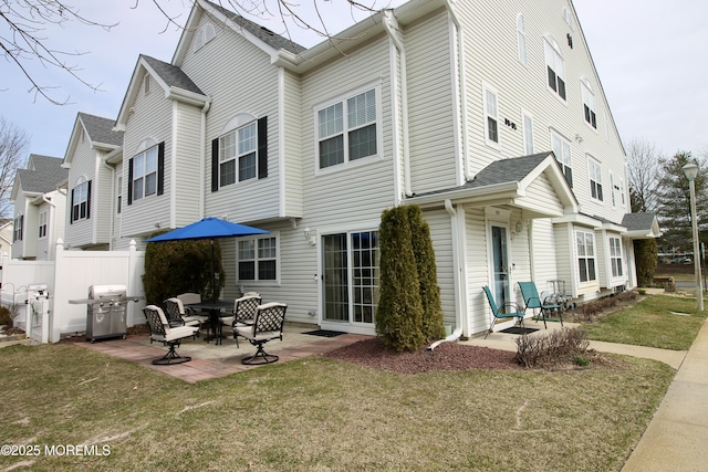 rear view of house featuring a yard, fence, a shingled roof, and a patio area