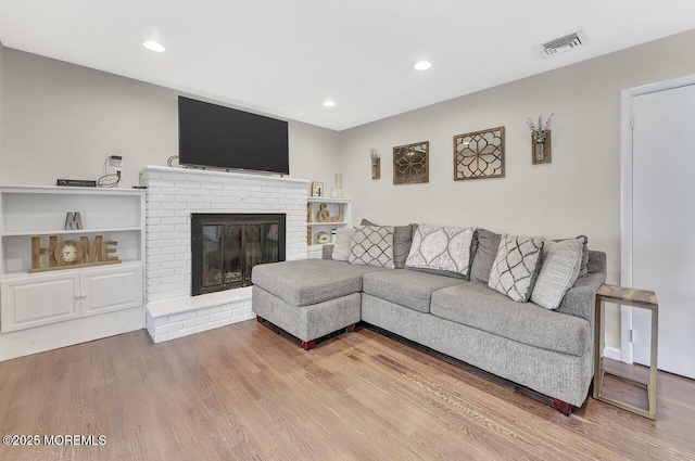 living room with visible vents, recessed lighting, a fireplace, and wood finished floors