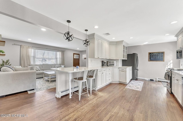 kitchen with visible vents, light wood finished floors, a peninsula, stainless steel appliances, and open floor plan