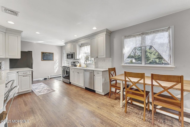 kitchen with visible vents, backsplash, light countertops, appliances with stainless steel finishes, and light wood-style floors