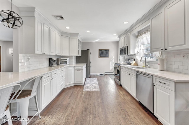 kitchen featuring wood finished floors, visible vents, a sink, appliances with stainless steel finishes, and white cabinetry