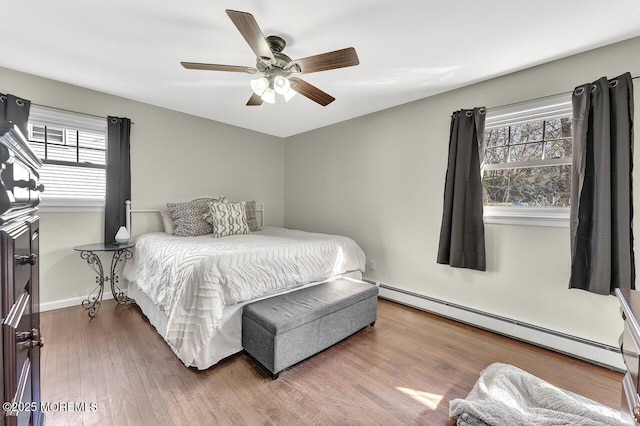 bedroom with baseboards, a baseboard heating unit, a ceiling fan, and wood finished floors