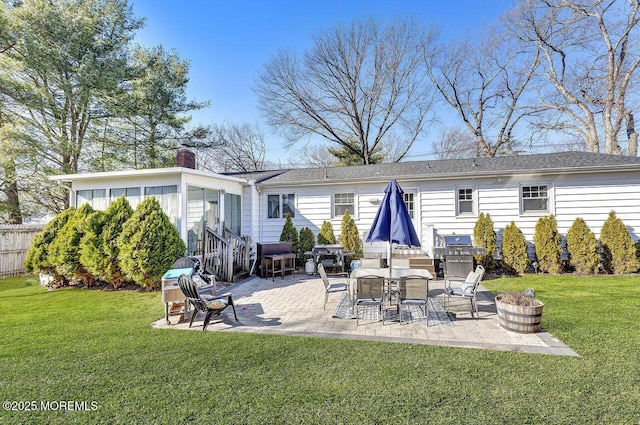 rear view of house with a patio area, a chimney, a yard, and fence