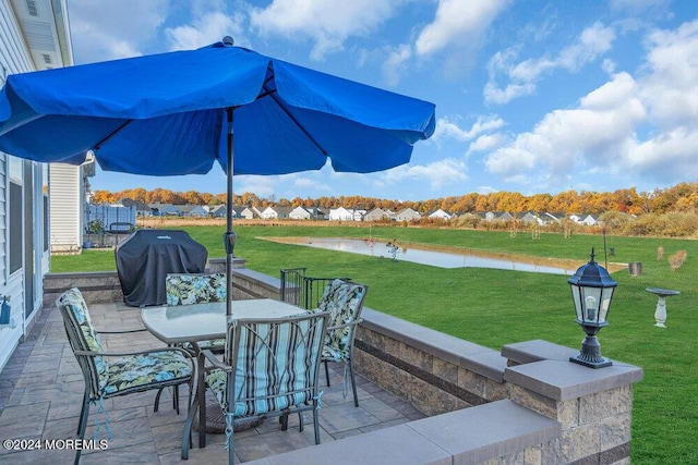 view of patio / terrace with grilling area, a water view, and outdoor dining area
