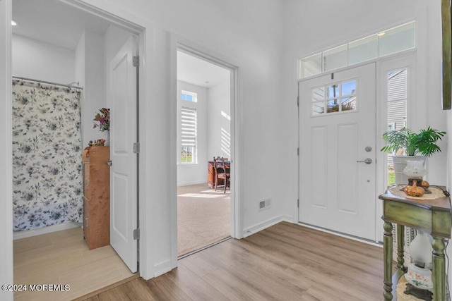 foyer entrance featuring light wood-type flooring, baseboards, and visible vents