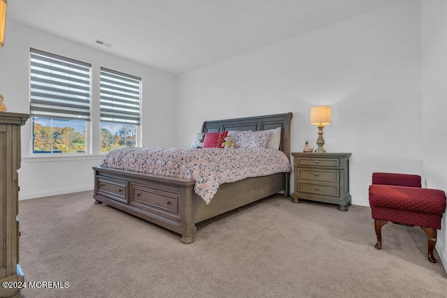 bedroom featuring visible vents, light carpet, and baseboards