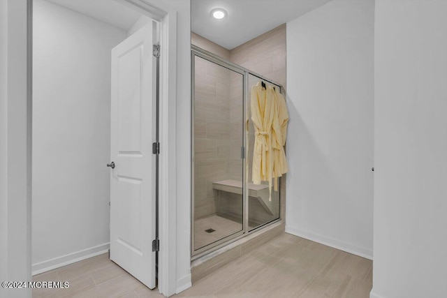 bathroom featuring a shower stall, wood finished floors, and baseboards