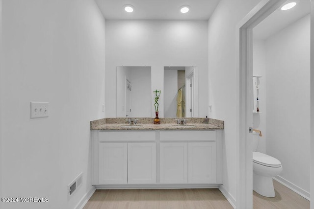 full bath featuring a sink, visible vents, toilet, and double vanity