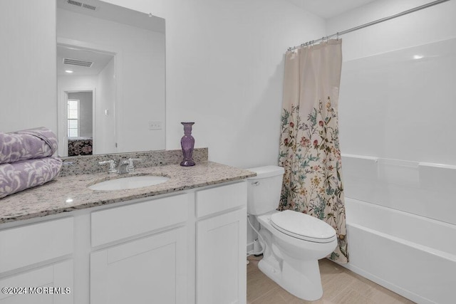 bathroom with vanity, shower / tub combo, toilet, and visible vents