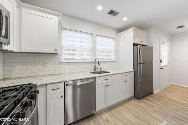 kitchen featuring light wood-type flooring, visible vents, appliances with stainless steel finishes, and a sink