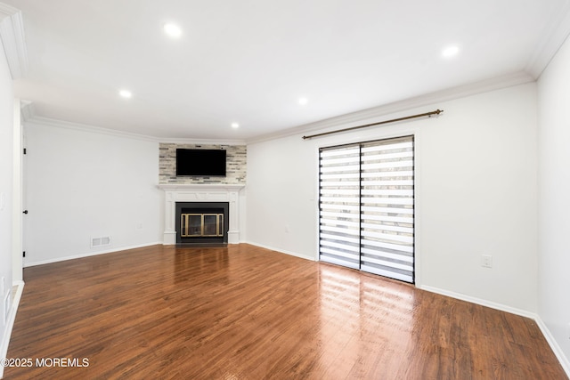 unfurnished living room featuring visible vents, ornamental molding, wood finished floors, a glass covered fireplace, and baseboards