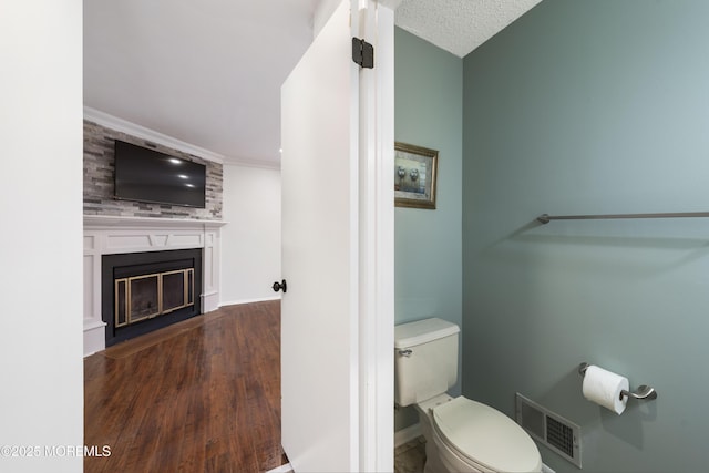 bathroom featuring visible vents, a large fireplace, baseboards, toilet, and wood finished floors