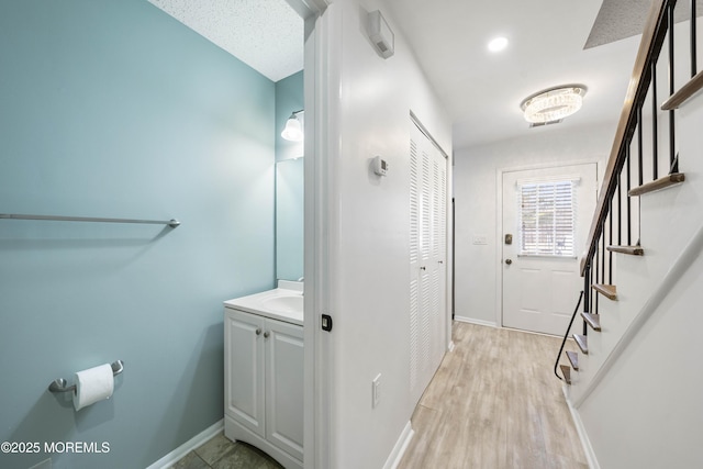 interior space with a sink, light wood-type flooring, baseboards, and stairs