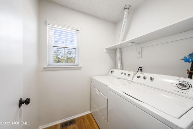 clothes washing area with baseboards, visible vents, laundry area, a textured ceiling, and washer and dryer