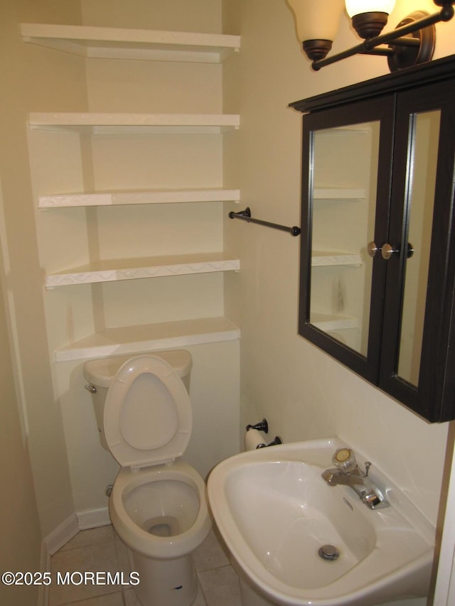 half bath with a sink, toilet, and tile patterned floors