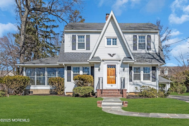 shingle-style home featuring a chimney, a shingled roof, and a front yard