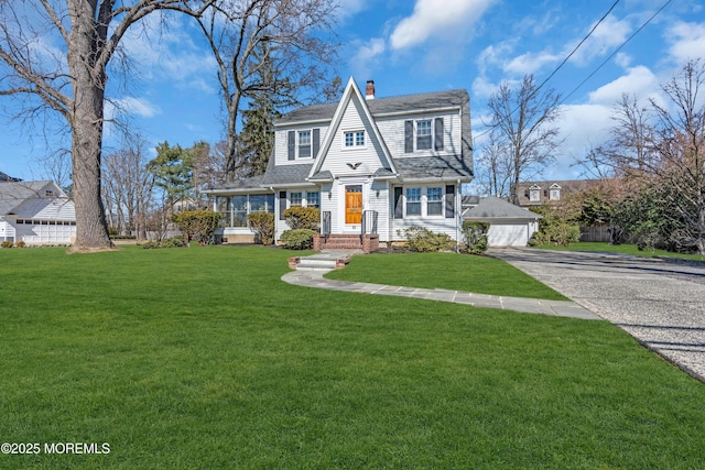 shingle-style home with a shingled roof, a front yard, and a chimney