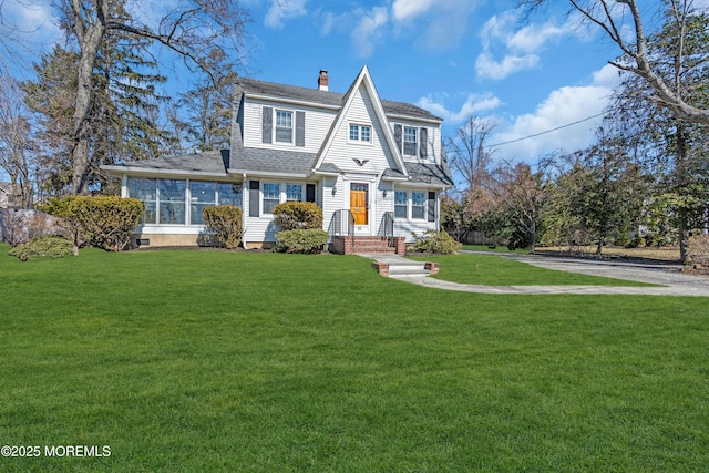 shingle-style home featuring a front lawn, roof with shingles, and a chimney