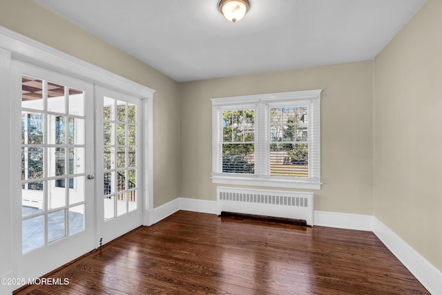 empty room featuring radiator heating unit, baseboards, and dark wood-style flooring