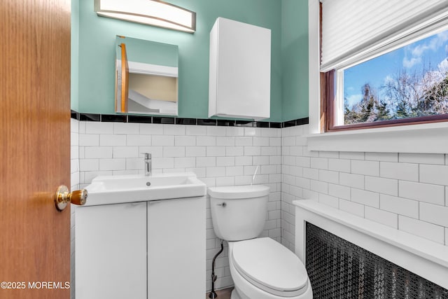 half bath featuring toilet, tile walls, and vanity