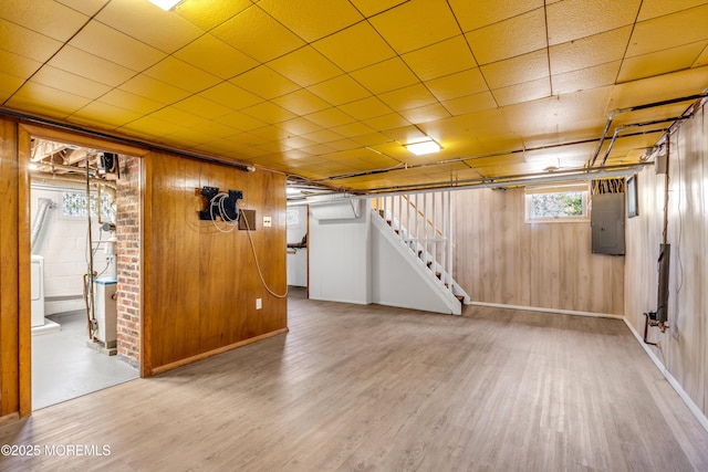 basement featuring electric panel, wood walls, stairs, and wood finished floors