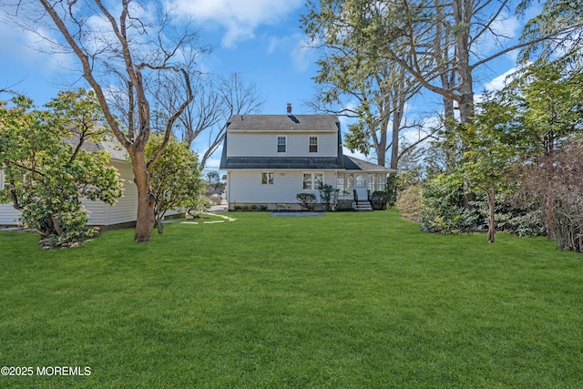 rear view of property featuring a lawn