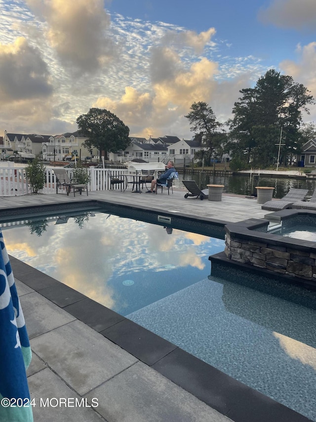 view of swimming pool featuring a patio, a residential view, and a pool with connected hot tub