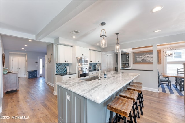 kitchen with visible vents, a sink, a kitchen breakfast bar, white cabinetry, and stainless steel appliances